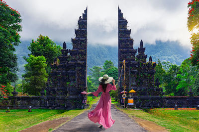 Rear view of woman with umbrella against sky