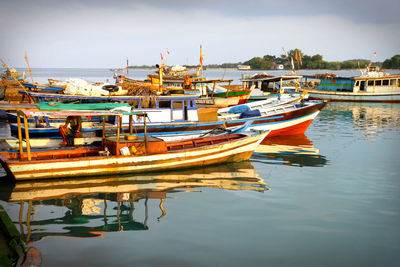 Boats moored at harbor against sky