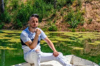 Portrait of smiling young man sitting against plants