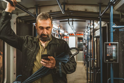 Man reading from mobile phone screen while traveling on metro. wireless internet on public transport