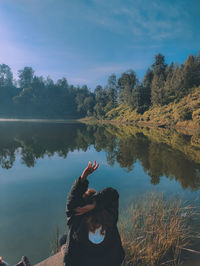 Rear view of woman looking at lake against sky