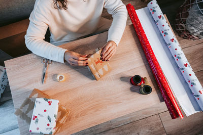 Midsection of woman packing christmas present by table