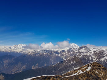 Scenic view of snowcapped mountains against blue sky