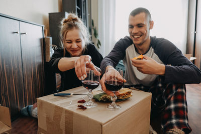 Cheerful couple having food and wine at home