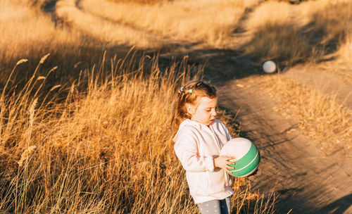 Cute little girl playing ball outdoors