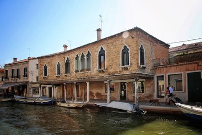 Buildings by canal against clear sky in city