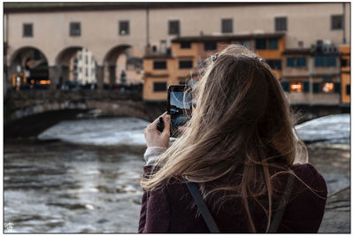 Rear view of woman photographing with city in background