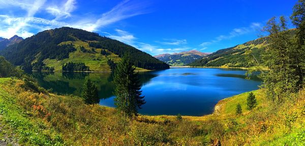 Scenic view of lake and mountains against blue sky