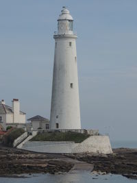 Lighthouse by sea against sky