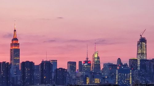 Illuminated buildings in city against sky during sunset