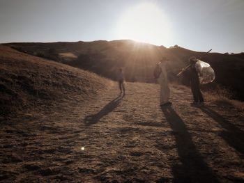 People walking on landscape at sunset