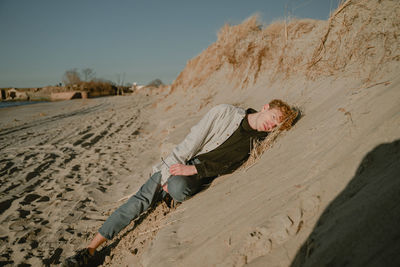 Young man lying on sand dune