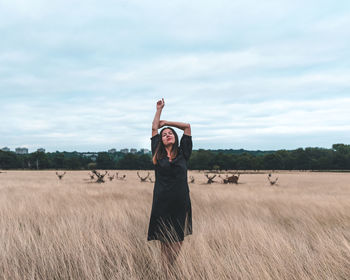 Full length of woman standing on field against sky