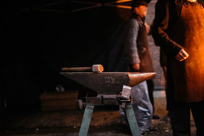 Hammer on metal with people standing in background