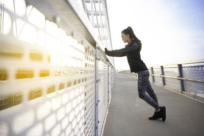 Side view of woman standing on bridge against sky