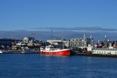 Scenic view of sea by buildings against blue sky