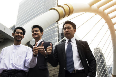 Businessmen gesturing thumbs up in city