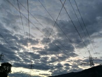 Low angle view of silhouette electricity pylon against sky