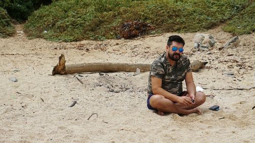 Young man sitting on sand