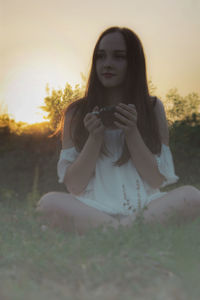 Young woman standing against tree during sunset