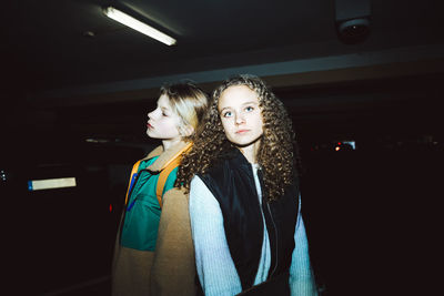 Portrait of girl with female friend standing in parking lot