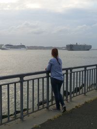 Boy on pier over sea against sky