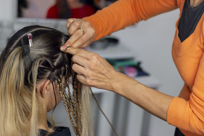 A stylist mother getting her teenage daughter senegalese braids in her home. 