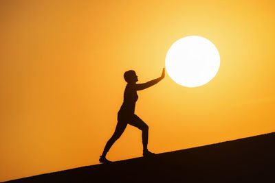 Silhouette man standing against orange sky