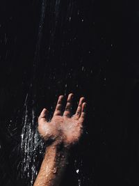 Water splashing on hand against black background