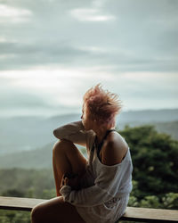 Young woman looking at sea against sky