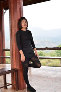 Young woman with eyes closed standing by column at observation point