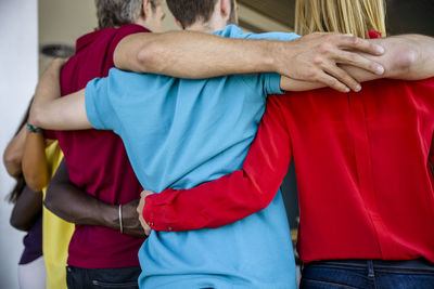 Male and female professionals with arms around standing at office