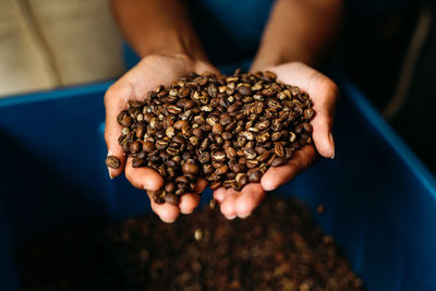 Cropped hands holding roasted coffee beans