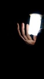 Close-up of hand holding illuminated lamp in darkroom