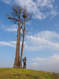 Rear view of woman standing on field against sky