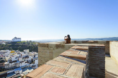 Man and buildings against clear blue sky