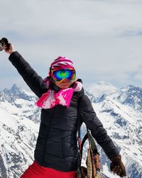 Woman with umbrella on snowcapped mountain against sky
