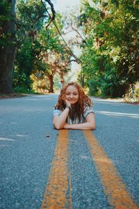 Portrait of a smiling young woman sitting on road