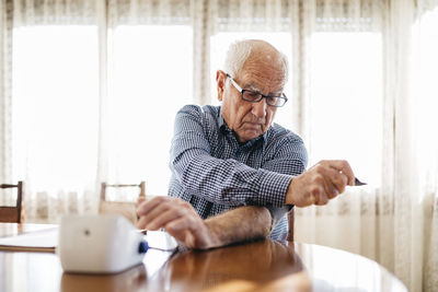 Senior man controlling his blood pressure at home