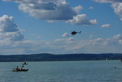 Helicopter flying over sea against sky