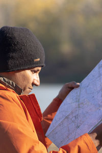 Portrait of traveler man at lake in autumn with a map