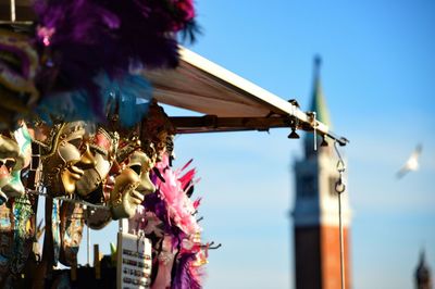 Masks hanging for sale by church of san giorgio maggiore against sky in city