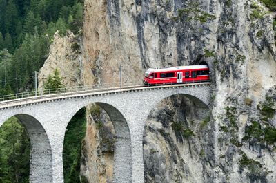 Red car on bridge against rock formation