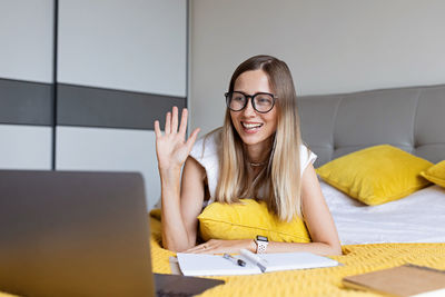 Smiling woman talking on video call on bed