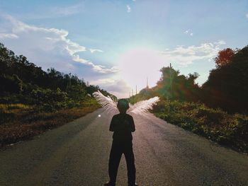 Rear view of man standing on road against sky