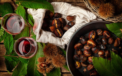 Top view of roasted chestnuts in iron skillet on wooden table.