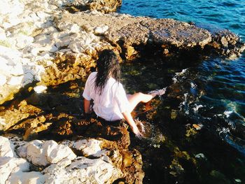 Rear view of woman on rock by sea
