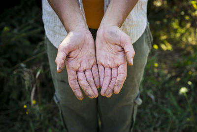 High angle view of beekeeper showing dirty hands while standing on field