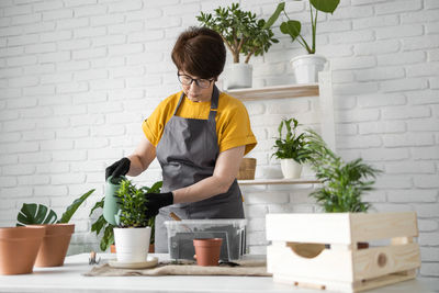 Side view of boy watering plants at home