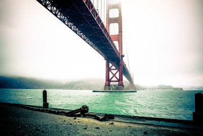 Suspension bridge over sea against sky